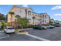 Beautiful condo complex featuring parking, tropical landscaping, and building with exterior stairwells at 4141 Hibiscus Dr. # 201, Little River, SC 29566