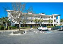 A multi-story condo building featuring stairs, white railings, and palm trees set against a clear blue sky at 6253 Catalina Dr. # 214, North Myrtle Beach, SC 29582