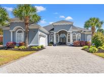 Stunning single-story home featuring a well-manicured lawn, brick driveway, and elegant architectural design at 8504 Juxa Dr., Myrtle Beach, SC 29579