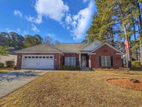 Charming brick home featuring a well-manicured lawn, two-car garage, and a welcoming entrance at 86 Old Barge Dr., Pawleys Island, SC 29585