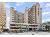 Exterior view of a high-rise condo building featuring well-maintained grounds and ample parking at 501 S Ocean Blvd. # 1002, North Myrtle Beach, SC 29582
