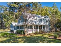 Charming two-story blue home featuring a lovely front porch and well-manicured landscaping at 160 Shipmaster Ave., Pawleys Island, SC 29585