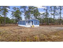 Charming blue home with a white porch nestled among tall trees at 1236 Heritage Rd., Loris, SC 29569