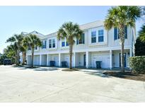 Charming townhomes featuring white siding, blue shutters, and lush palm trees creating a serene coastal living environment at 4850 Cantor Ct. # 202, North Myrtle Beach, SC 29582