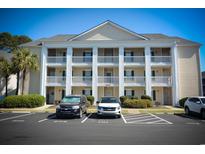 Three-story condo building with white pillars and reserved parking spaces for residents and guests at 5030 Windsor Green Way # 203, Myrtle Beach, SC 29579