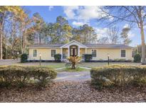 Charming single-story home with a yellow exterior, black front door, and a circular driveway at 5825 Peachtree Rd., Myrtle Beach, SC 29588