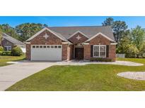 Charming brick home featuring an attached two-car garage and manicured lawn at 615 Woodbine Ct., Myrtle Beach, SC 29579