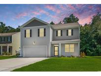 Charming two-story home featuring a well-manicured lawn, attached garage and neutral gray siding at 878 Snowberry Dr., Longs, SC 29568