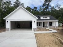New construction single-story home with white siding, stone accents, open garage, and a concrete driveway and sidewalk at 1274 Pinetucky Dr., Galivants Ferry, SC 29544