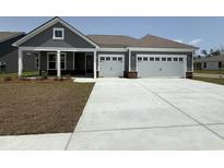Charming home exterior features a two-car garage, gray siding, and a well-manicured lawn at 242 River Edge Dr., Myrtle Beach, SC 29588