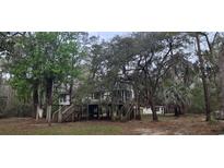 Exterior view of elevated home with surrounding lush trees and established landscaping at 1030 Waccamaw Lake Dr., Conway, SC 29526