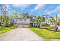 Charming two-story home with attached two-car garage, lush lawn, and tropical landscaping at 1421 Cottesmore Ct., North Myrtle Beach, SC 29582