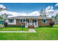 Charming single-story brick home featuring a welcoming front porch and a well-manicured lawn at 144 Pink Dogwood Dr., Loris, SC 29569