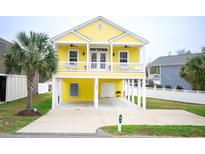 Bright yellow home with a covered carport, a second story porch and a palm tree at 1965 24Th Ave. N, North Myrtle Beach, SC 29582