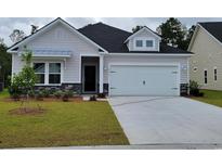 Charming single-Gathering home featuring a two-car garage, stone accents, manicured lawn, and modern architectural details at 2030 Lone Cypress Dr, Myrtle Beach, SC 29579
