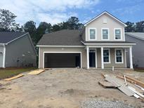Exterior view of a two-story home with tan siding and an unfinished yard showcasing construction in progress at 393 Sun Colony Blvd., Longs, SC 29568