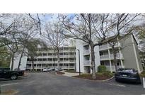Three-story condo building with multiple balconies, gray siding, and ample parking at 415 Ocean Creek Dr. # 2443, Myrtle Beach, SC 29572