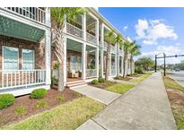 Charming townhouse exterior with brick facade, white columns, and breezy balconies lined with lush palm trees at 2790 Howard Ave. # D, Myrtle Beach, SC 29577