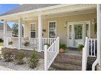 Inviting front porch with brick steps, white railings, and plants offers a charming welcome to this cozy home at 441 Garden Ave., Georgetown, SC 29440