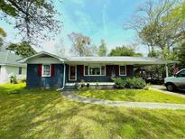 Charming home featuring a painted brick exterior, red shutters, well-manicured lawn, and a covered carport at 710 62Nd Ave. N, Myrtle Beach, SC 29572