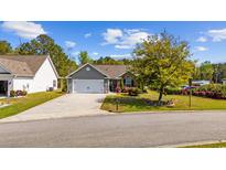 Charming single-story home featuring a manicured lawn, mature tree, and a two-car garage at 90 Carolina Crossing Blvd., Little River, SC 29566