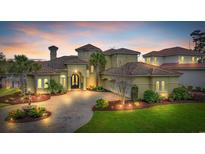 Stately Mediterranean home with tile roof, manicured landscaping, and paver driveway at sunset at 9243 Marina Pkwy., Myrtle Beach, SC 29572
