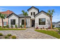 Beautifully landscaped home exterior featuring a paver driveway, manicured lawn, and stucco facade with stone accents at 134 Avenue Of The Palms, Myrtle Beach, SC 29577