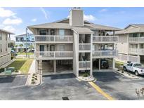 A three story condo building with a light grey exterior, multiple balconies, and parking underneath the units at 1801 N Ocean Blvd. # O-4, North Myrtle Beach, SC 29582