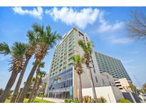 Beautiful high-rise condo building with tropical landscaping, palm trees, and clear blue sky at 201 74Th Ave. N # 1128, Myrtle Beach, SC 29572