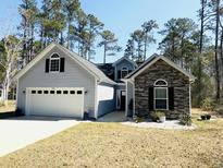 Charming home featuring a two-car garage, stone accents, and complemented by a beautifully landscaped front yard at 480 N Boundaryline Dr. Nw, Calabash, NC 28467