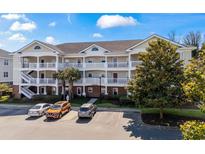 Three story condo building with balconies and parking spots in front surrounded by green trees and landscaping at 5751 Oyster Catcher Dr. # 234, North Myrtle Beach, SC 29582