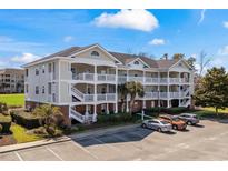 Attractive three-story condo building featuring a large parking area, manicured landscaping, and golf course views at 5751 Oyster Catcher Dr. # 234, North Myrtle Beach, SC 29582