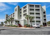 Sands Beach Club boasts light green siding, multiple balconies, and lush palm trees surrounding its entrance at 9400 Shore Dr. # 506, Myrtle Beach, SC 29572
