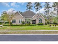 Charming single-story brick home featuring manicured lawn and lush landscaping with mature trees and an inviting entrance at 152 Creek Harbour Circle, Murrells Inlet, SC 29576