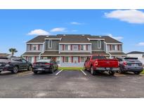 View of the condo complex with gray siding, red shutters, and ample parking on a sunny day at 1851 Colony Dr. # 6J, Myrtle Beach, SC 29575