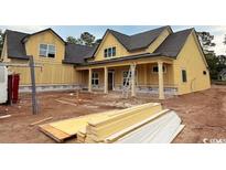 Spacious new construction home with yellow siding, a covered porch, and visible construction materials at 804 Edisto Ct., Myrtle Beach, SC 29588