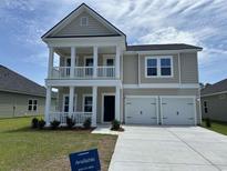 Charming two-story home featuring a welcoming front porch and a two-car garage, inviting curb appeal at 3329 Sw Wood Stork Dr., Ocean Isle Beach, NC 28469