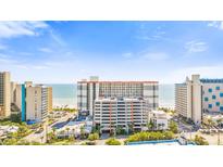 Wide view of the condo complex on the beach with an attached parking garage and blue skies at 7200 N Ocean Blvd. # 1053, Myrtle Beach, SC 29572