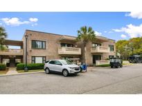 A two-story brick condo building featuring a palm tree and parked golf carts at 10100 Lakeshore Dr. # C-1, Myrtle Beach, SC 29572