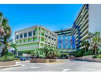 View of the exterior of the Coral Beach Resort, featuring a light green facade and tropical landscaping at 1105 S Ocean Blvd. # 502, Myrtle Beach, SC 29577
