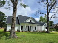 Attractive modern farmhouse with covered front porch, black trimmed windows and professionally landscaped yard at 1464 Hawthorn Dr., Pawleys Island, SC 29585