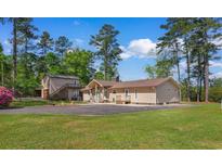 Tan house with large driveway and 2-story building surrounded by green grass and tall trees under blue sky at 164 Mohican Dr., Georgetown, SC 29440