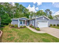 Charming blue home boasts an attached garage, well-kept lawn, and landscaped flower beds at 1804 Fairbanks Dr., Conway, SC 29526