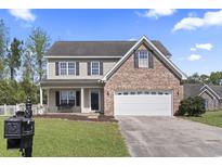 Charming two-story home featuring a brick accent, an attached garage and a well manicured lawn at 211 Oak Landing Dr., Conway, SC 29527
