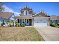 Charming two-story home featuring a well-manicured lawn, a two-car garage and a welcoming front porch with blue chairs at 2324 Tidewatch Way, North Myrtle Beach, SC 29582