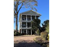 Three-story home featuring columned balconies, manicured landscaping, and a brick driveway leading to the house at 234 Ave. Of The Palms, Myrtle Beach, SC 29579