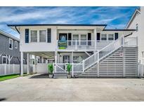 Two story beach house featuring elevated structure, white siding, and a double staircase at 329 46Th Ave. N, North Myrtle Beach, SC 29582