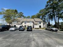 Condominium complex surrounded by tall trees, featuring ample parking and neutral toned facade at 4482 Little River Inn Ln. # 2004, Little River, SC 29566