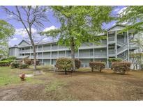 Multi-level condo building with wooden stairs and walkways, mature landscaping, and a fire hydrant in front at 5905 South Kings Hwy. # 4202, Myrtle Beach, SC 29575