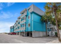 Charming beach condo building featuring light blue exteriors, white railings, and ample parking at 720 North Waccamaw Dr. # 312, Murrells Inlet, SC 29576